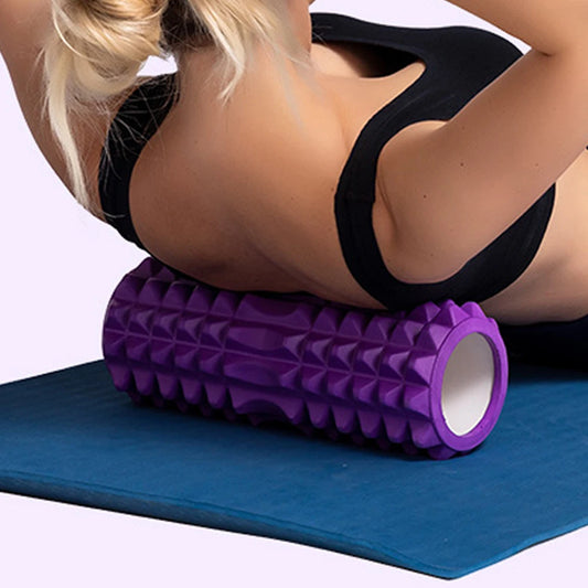Vrouw gebruikt een paarse foam massage roller voor haar rug tijdens een ontspannende yogasessie
